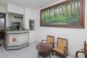 a room with a table and chairs and a painting on the wall at RedDoorz near Stasiun Malang Kota Lama 2 in Malang