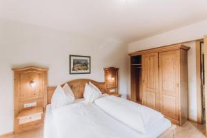 um quarto com uma cama branca e armários de madeira em Grassbichlhof em Altenmarkt im Pongau