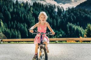 mała dziewczynka w różowej sukience jeżdżąca na rowerze w obiekcie Grassbichlhof w mieście Altenmarkt im Pongau