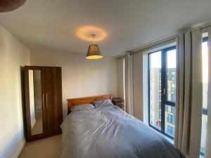 a bedroom with a bed and a large window at Rooms in exquisite and centrally located apartment in Colindale