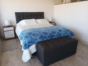 1 dormitorio con cama y reposapiés negro en Edificio WAVE Costa Montemar concon, en Concón