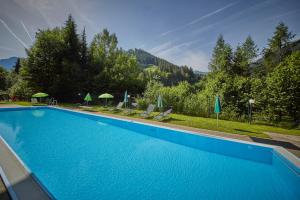 ein großer blauer Pool mit Stühlen und Sonnenschirmen in der Unterkunft AlpenParks Apartment & Ferienresort Rehrenberg Viehhofen in Viehhofen