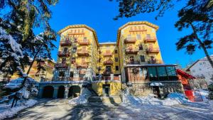 a large yellow building with snow on the ground at Appartamento Frejus - Affitti Bevi Italia in Bardonecchia