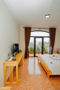 a bedroom with a bed and a desk and a television at Sea and Sand Hotel in Hoi An