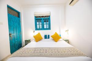 a bedroom with a bed with blue doors and yellow pillows at Moi Galle Fort by DBI in Galle