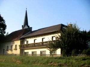 ein großes weißes Haus mit einem Kirchturm darüber in der Unterkunft Gasthof Kaiser in Sankt Veit an der Glan