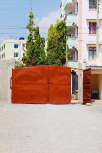 a large orange gate with plants on top of it at Mtwapa Apartment in Mombasa