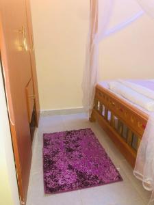 a bedroom with a purple rug next to a bed at Mtwapa Apartment in Mombasa