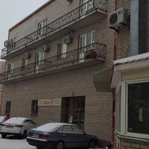 two cars parked in front of a brick building at Гостиница ,,Меркурий и К,, in Astana