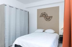 1 dormitorio con 1 cama blanca y 2 almohadas en LE LUCIEN Eco-Appart'Hôtel - Angouleme - Centre - Wifi - Parking privé - Classé 4 étoiles, en Angulema