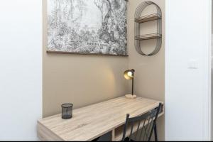 una mesa de madera en una habitación con lámpara en LE LUCIEN Eco-Appart'Hôtel - Angouleme - Centre - Wifi - Parking privé - Classé 4 étoiles, en Angulema