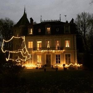 Uma casa velha com luzes de Natal à frente. em Château de Corcelle - Chambres et table d'hôtes em Châtenoy-le-Royal