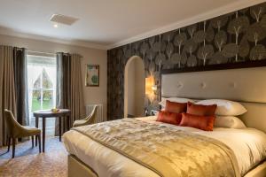 a hotel room with a large bed and a table at Oakley Hall Hotel in Basingstoke
