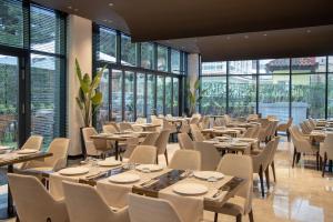 a dining room with tables and chairs and windows at Hotel Elisa Tirana, Affiliated by Meliá in Tirana