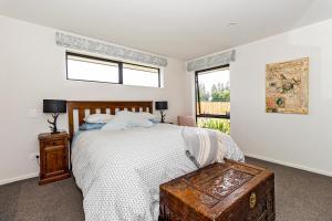 a bedroom with a bed with a wooden table and two windows at Just like home - Methven in Methven