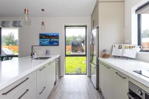 a kitchen with white cabinets and a large window at Just like home - Methven in Methven