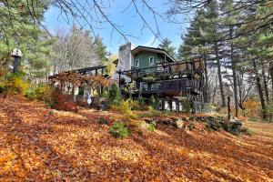a house in the woods with leaves on the ground at The Green House- Killington's Most Unique Ski Home home in Killington