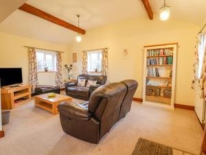 a living room with a leather couch and a tv at Mill Lane Cottage in Chester