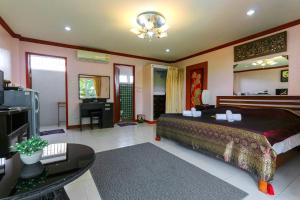 - une chambre avec un grand lit et une télévision dans l'établissement The Phen House, à Hua Hin