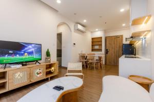 a living room with a large tv and a kitchen at Ecopark - Lullaby Home Ecopark in HÆ°ng YÃªn