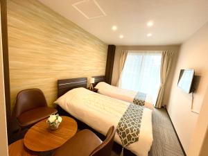 東京にあるSugamo Winco Residenceのベッド2台、テーブルと椅子が備わるホテルルームです。