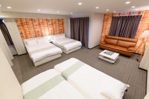 東京にあるSugamo Winco Residenceのベッド2台とソファが備わるホテルルームです。
