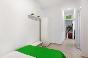een witte slaapkamer met een groene deken op een bed bij Jardin Cardona in Arucas