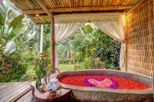 a large bath tub filled with red and purple flowers at Fivelements Retreat Bali in Ubud