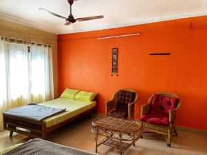 a bedroom with orange walls and a bed and two chairs at Sandev Homestay in Madikeri