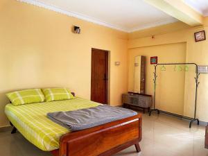 a bedroom with a bed in a room with yellow walls at Sandev Homestay in Madikeri