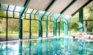 ein Pool mit Fenstern und eine Person im Wasser in der Unterkunft Relais & Chateaux Hotel Hohenhaus in Herleshausen