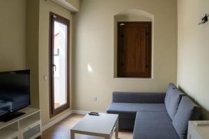 ein Wohnzimmer mit einem Sofa und einem TV in der Unterkunft Optimus Apartments Corazón de Triana in Sevilla