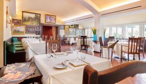 a restaurant with white tables and chairs and windows at Relais & Chateaux Hotel Hohenhaus in Herleshausen