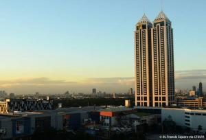 a view of a city with a tall building at Romantic 1 Bedroom with Pool in Manila