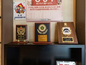 a shelf with three different awards on it at Aqua Garden Hotel Fukumaru in Kagoshima