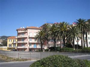 a building with palm trees in front of a street at Hotel Corallo in Finale Ligure