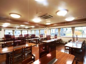 un restaurante con mesas y sillas de madera y ventanas en Hotel Meribel Tsugaike, en Otari