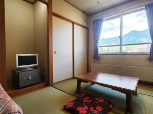sala de estar con mesa y TV en Hotel Meribel Tsugaike, en Otari
