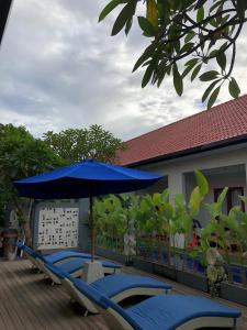 a row of blue chairs and an umbrella on a deck at Dewi Dewi Villas in Sanur