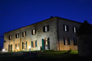 un gran edificio de ladrillo por la noche con sus luces encendidas en Podere Campiano, en Volterra