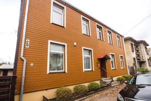 una casa de madera con un coche aparcado delante de ella en Kauko Laiptu Apartment, en Kaunas
