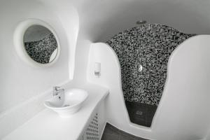 a white bathroom with a sink and a mirror at Vogue Suites in Oia