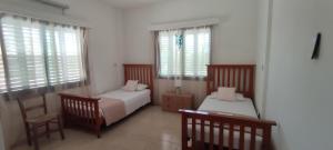 a bedroom with two beds and two chairs and windows at Oasis Nature in Polis Chrysochous