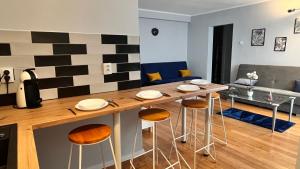 a kitchen and living room with a table and stools at Apartament z widokiem na Spodek in Katowice