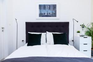 1 dormitorio con 1 cama blanca grande con almohadas verdes en Five Forty Five Studios by Irundo en Zagreb