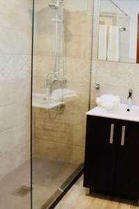 een badkamer met een glazen douche en een wastafel bij Tuent in Port de Pollença