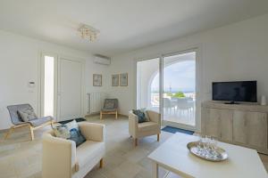 - un salon avec une télévision, un canapé et une table dans l'établissement Villa Arca by RivedelSalento, à Otrante