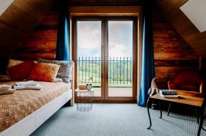 um quarto com uma cama e uma grande janela em LassChata - Domki w górach z balią em Zakopane