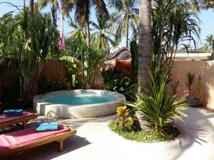 a backyard with a swimming pool and a palm tree at Santan Gili Cottages in Gili Trawangan