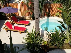 a pool with two lounge chairs and an umbrella at Santan Gili Cottages in Gili Trawangan